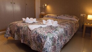 A neatly made bed with floral bedding, a bedside lamp, and a wall-mounted light fixture. - La Terrasseta. Ático con terraza. (Graus)