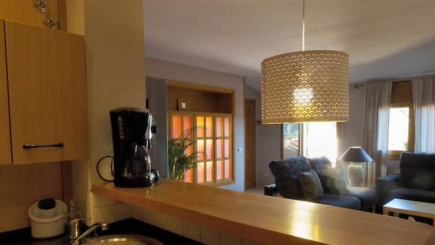 A modern kitchen with a coffee maker, a sink, and a dining area with a sofa and table. - La Terrasseta. Ático con terraza. (Graus)