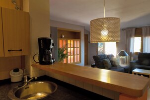 Una cocina moderna con cafetera, pileta y comedor con sofá y mesa.
