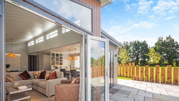 A modern open-plan living area with a sofa, coffee table, and dining table. - 2 bedroom accommodation in Benllech (Benllech)