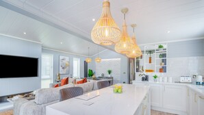 A modern kitchen with white cabinets, a marble island, and pendant lighting. - 2 bedroom accommodation in Benllech (Benllech)