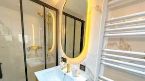 A modern bathroom with a white sink, gold fixtures, a large mirror with a gold frame, and a glass shower enclosure. - 1 Bedroom Apartment in L'Isle-sur-la-Sorgue (L'Isle-sur-la-Sorgue)