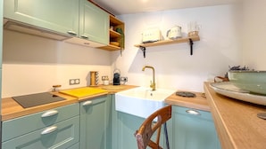 A kitchen with teal cabinets, a wooden countertop, a sink, and a chair. - 1 Bedroom Apartment in L'Isle-sur-la-Sorgue (L'Isle-sur-la-Sorgue)