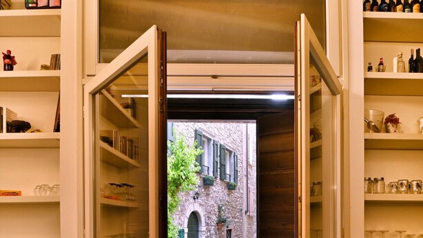 A doorway leading to a cobblestone street with a stone building and greenery. - Appartamento Simone by Theater Home, in the heart of Gargnano (Gargnano)