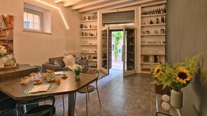 A modern living room with a dining area, open shelving with books and decorative items, and a view of the outdoors. - Appartamento Simone by Theater Home, in the heart of Gargnano (Gargnano)