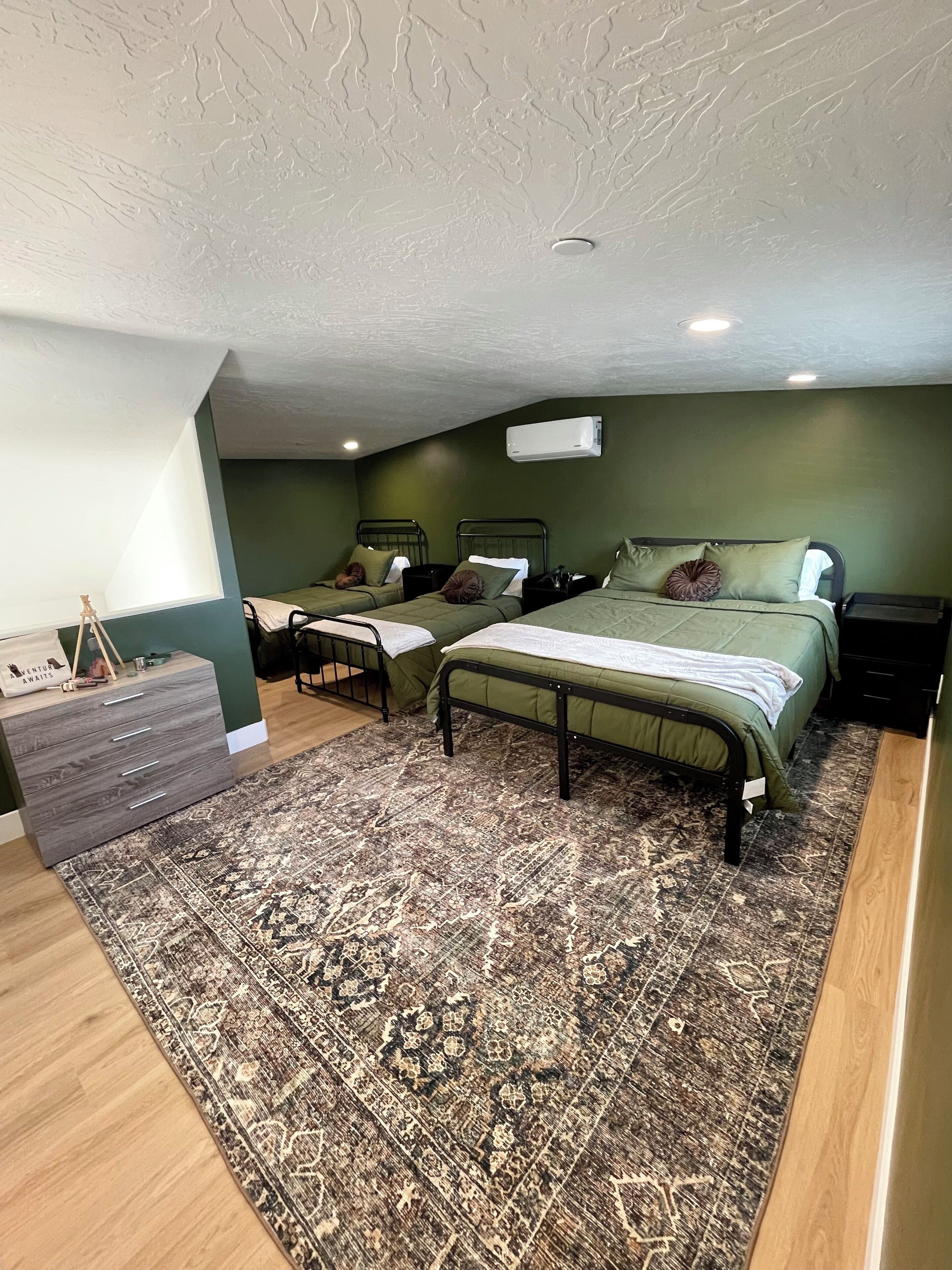 A bedroom with two single beds, a dresser, and a patterned rug.