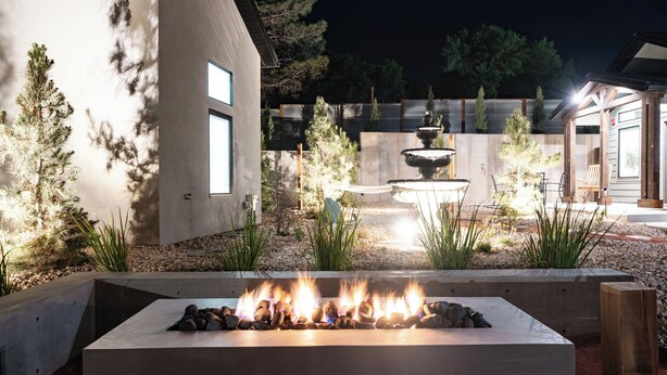A modern outdoor patio with a fire feature, a stone planter, and a wooden pergola. - Zion Oasis Rentals (Hurricane)
