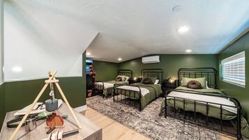 Een kamer met drie stapelbedden, een houten tafel met kampeeruitrusting en een kamerkleed met een patroon.