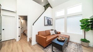 A modern living room with a brown leather sofa, a black coffee table, and a large green plant. - Zion Oasis Rentals (Hurricane)