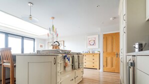 Een keuken met een centraal eiland, houten kasten, een houten deur en een raam.