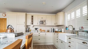 Een moderne keuken met witte kasten, een houten eettafel en een ingebouwde magnetron.