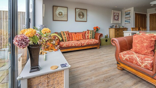 Een ruime woonkamer met een groot raam, een bank, een salontafel en een eethoek.
