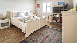 Een slaapkamer met een bed, nachtkastjes, een raam, een plank met handdoeken en een vloerkleed.