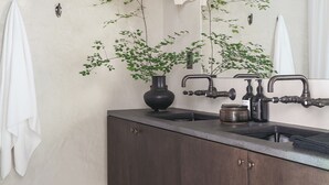 Un baño moderno con tocador de madera oscura, un espejo grande y dos grifos empotrados.