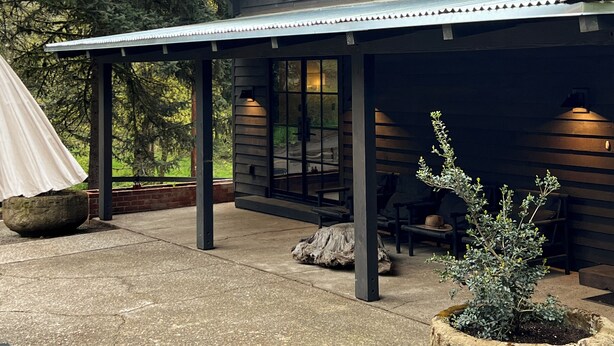 Una casa moderna con un porche cubierto, ventanas amplias y una jardinera de piedra.