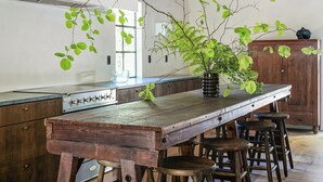 Una cocina con una barra de madera, taburetes y una planta en maceta.