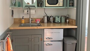 Una cocina compacta equipada con microondas, cafetera y refrigerador pequeño.