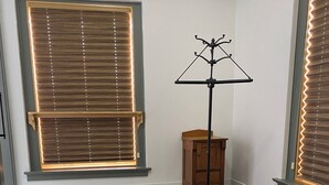 Un dormitorio con cama, una ventana con persianas, un radiador y un armario de madera.