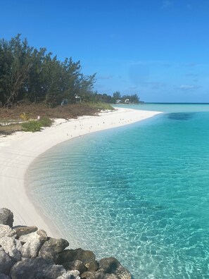 A beach with clear turquoise water, white sand, and a rocky foreground. - Ocean View, Sleeps 8, SUP, Beach Toys (Spanish Wells)