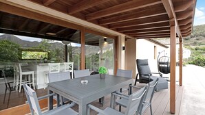 Eine Terrassengaststätte mit Holzboden, einem Esstisch, Stühlen und einem kleinen Blumentopf.