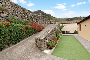 A stone wall, a green lawn, and a building with a tiled roof.