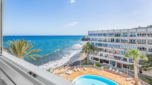 Ett hotell med pool, utsikt över stranden och flera balkonger.