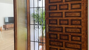 An open wooden door with a patterned design, leading to a room with a television and a potted plant. - Holiday Home 'Villa Gracia' with Sea View, Wi-Fi and Air Conditioning (Mijas)