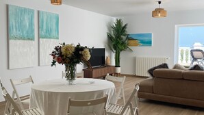 A modern living room with a round dining table, white chairs, a brown sofa, and a large window with a view. - Holiday Home 'Villa Gracia' with Sea View, Wi-Fi and Air Conditioning (Mijas)