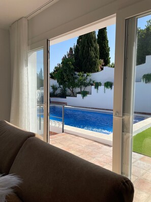 A room with a view of a swimming pool, a glass door, and a couch.