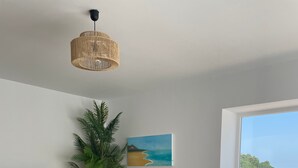 A modern living room with a sofa, television, plant, painting, and a view through a window. - Holiday Home 'Villa Gracia' with Sea View, Wi-Fi and Air Conditioning (Mijas)