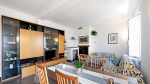 Un salon moderne comprenant une table à manger, des chaises, un canapé et un coin cuisine avec des placards et un téléviseur.
