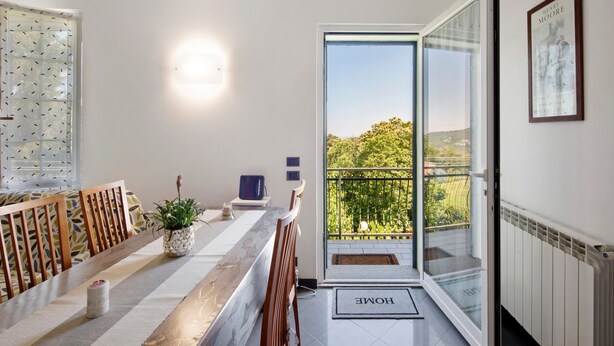 Un intérieur moderne comprenant un coin repas, une plante en pot, un tableau encadré et un balcon avec vue.