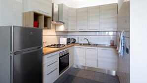 Une cuisine moderne dotée d’appareils électroménagers en acier inoxydable, de meubles en bois et d’un four encastré.