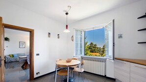 Une cuisine moderne avec un coin repas, une grande fenêtre offrant une belle vue et une porte en bois donnant sur une autre pièce.