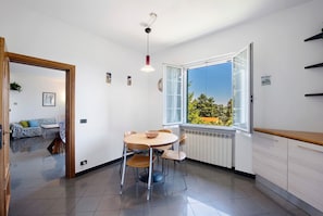 Eine moderne Küche mit Essbereich, einem großen Fenster mit Blick und einer Holztür zu einem weiteren Raum.
