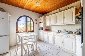 A kitchen with white cabinets, a white table, and a window with a view.