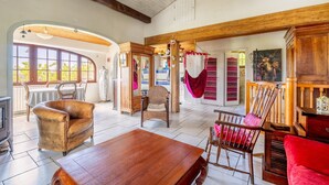 A spacious room with a wooden ceiling, a large window, a fireplace, and a dining area. - Bois Flottés Holiday Home – House with Garden, 700 Meters from the Sea (Pornic)