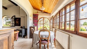 A dining area with a table, chairs, and a view through large windows. - Bois Flottés Holiday Home – House with Garden, 700 Meters from the Sea (Pornic)