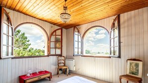 A room with wooden walls, a bed, a bench, and large arched windows. - Bois Flottés Holiday Home – House with Garden, 700 Meters from the Sea (Pornic)