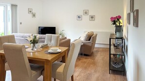 Un salon moderne avec une table à manger, des canapés et un téléviseur.