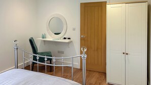 Une chambre à coucher comprenant un lit, un bureau avec un miroir, une chaise et une armoire.