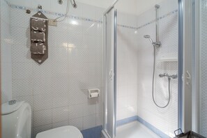 A bathroom with a shower, toilet, and a towel rack.