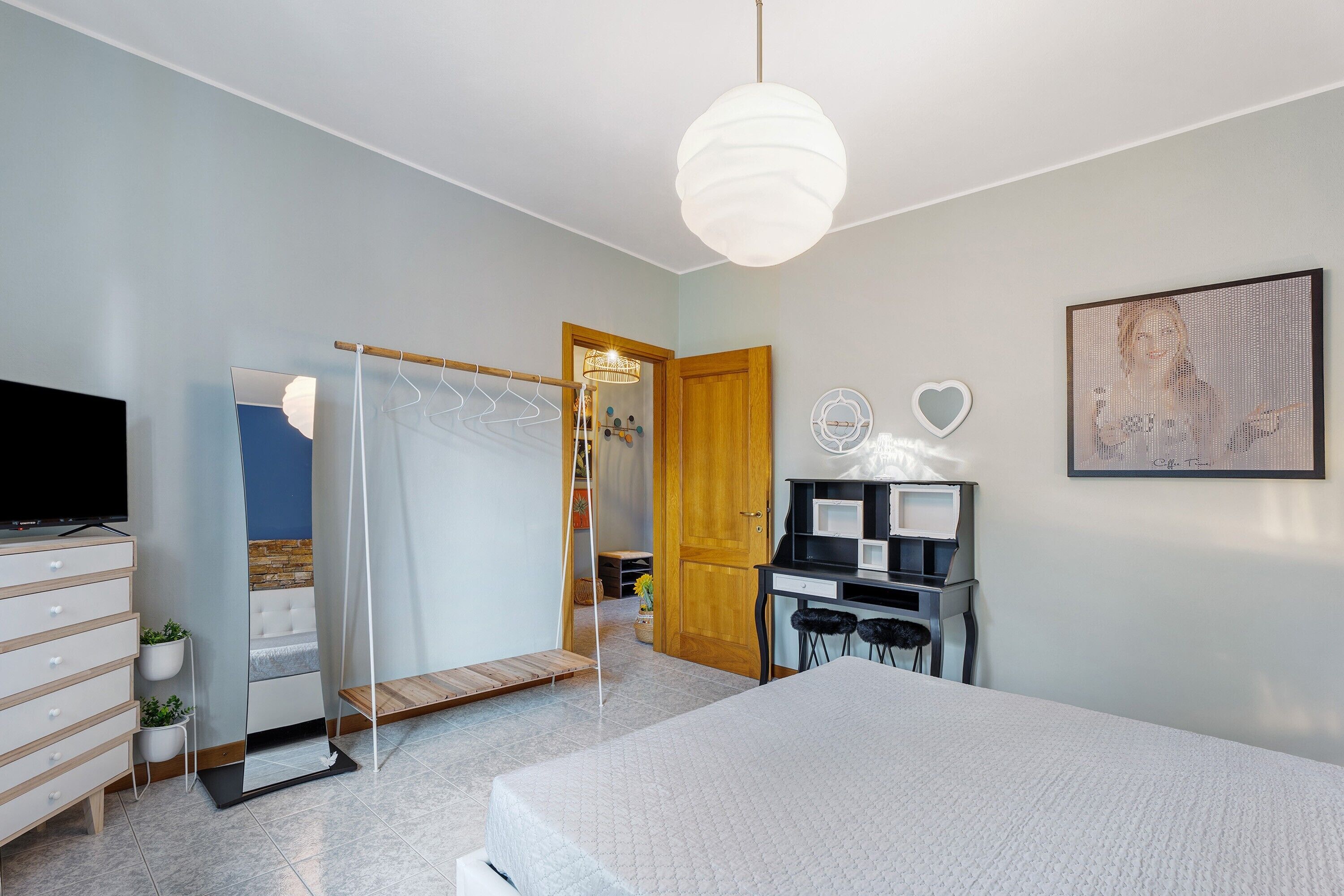 A bedroom with a bed, a TV, a desk, and a wardrobe.