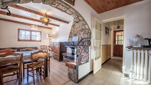 A dining area with wooden furniture, a stone archway, and a kitchen with a radiator. - Apartment 'Chalet -Les Aiguilles- Rdc' with Mountain View, Terrace and Garden (Albiez-Montrond)