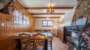 A wooden dining area with a table and chairs, a chandelier, and a stone wall. - Apartment 'Chalet -Les Aiguilles- Rdc' with Mountain View, Terrace and Garden (Albiez-Montrond)