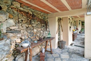 Eine rustikale Steinmauer mit verschiedenen Werkzeugen und einem Holztisch, auf dem ein Topf und eine Schüssel stehen.
