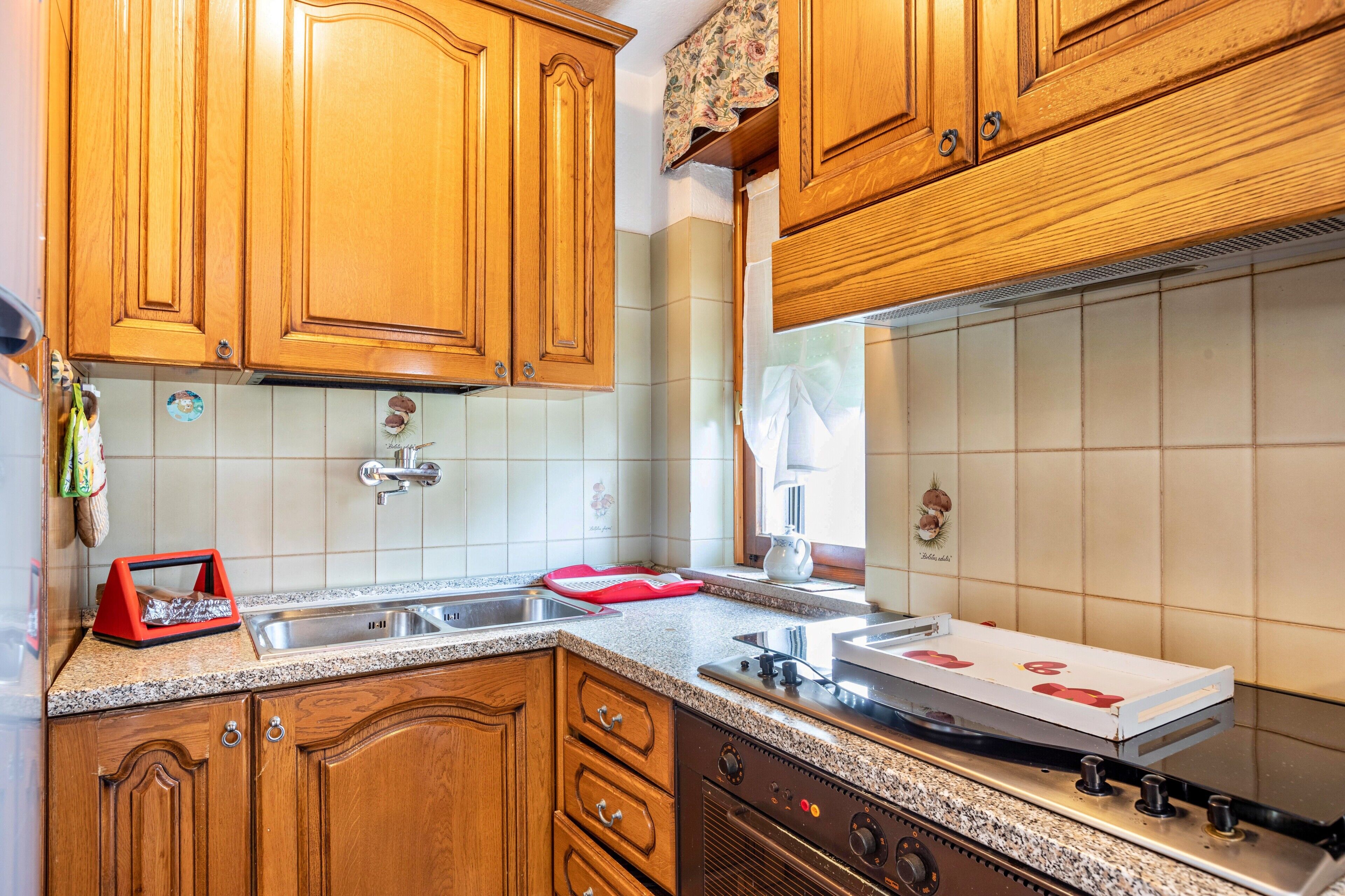 A kitchen with wooden cabinets, a granite countertop, a stainless steel sink, and a gas stove.