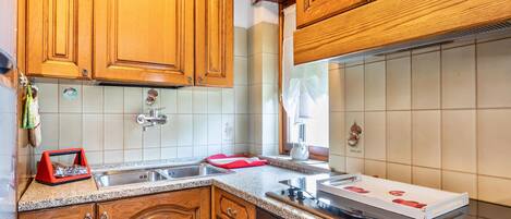 A kitchen with wooden cabinets, a granite countertop, a stainless steel sink, and a gas stove.