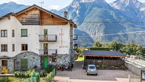 Ein Hotel mit Blick auf die Berge, mit einer Steinfassade, einem Balkon und einem Restaurantbereich.