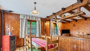 Ein Holzinnenraum mit einem Esstisch, Stühlen, einem Fernseher und einem roten Gerät.